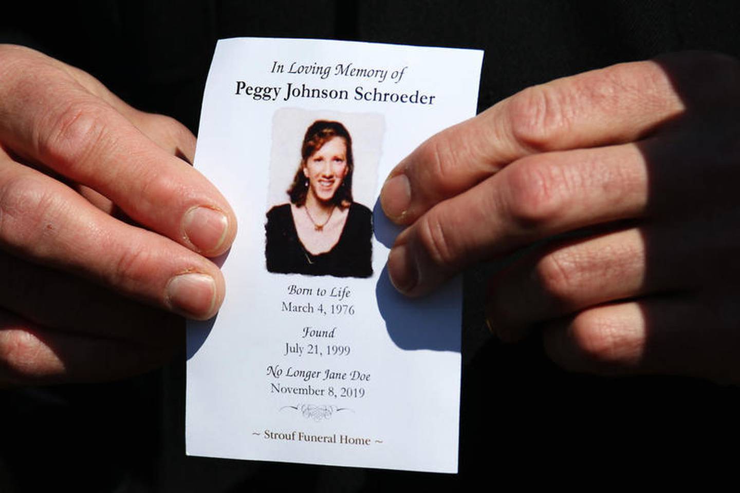 Racine County Sheriff Christopher Schmaling holds a prayer card for Peggy Lynn Johnson-Schroeder after a reburial service on her birthday at a plot next to her mother on Wednesday at Highland Gardens of Memories in Belvidere. Peggy Lynn Johnson-Schroeder was found dead at 23 years old in Racine in 1999 and was unidentified, known only as Jane Doe, until this past November when Linda La Roche was arrested in Cape Coral, Florida, for her murder.