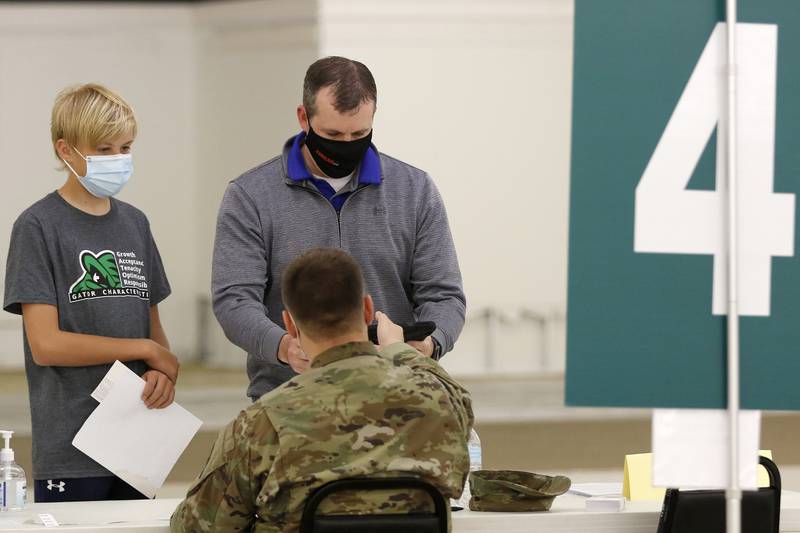 Crystal Lake South High School freshman Jack Dacy, 14, of Crystal Lake, checks in with his father, Dan Dacy, to get a Pfizer COVID-19 vaccine during a clinic run by the McHenry County Department of Health on Thursday, May 20, 2021, in McHenry.