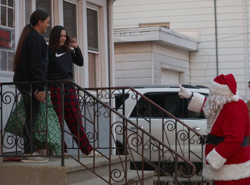 Santa delivers gifts to Kailynn Gerace and her mom Taylor near the intersection of 2nd and Calhoun Street as he delivers gifts to over 120 kids through the through Blue and Red Christmas for Kids on Friday, Dec. 19, 2025 in Peru. The Christmas program was established in 2013 by the Peru police and fire departments. It donates more than gifts to children in need.