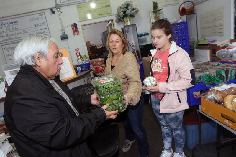 Hector Reyes, of Round Lake Beach works with Michele Pimpo and her daughter, Riley, 11, to get containers of organic spinach ready to distribute to patrons at the P.L.A.N. Food Pantry in Round Lake Beach.
