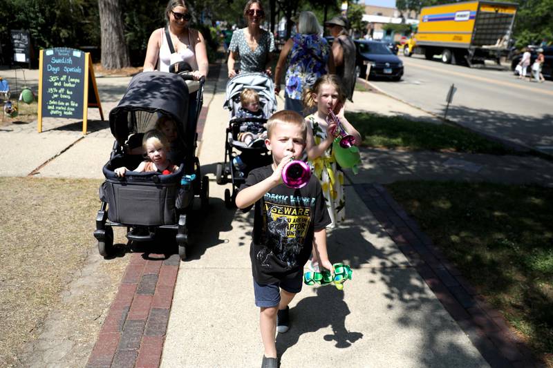 Ben White, 5, of Sycamore leads the way with Charlotte Dore, 6, of Plainfield as they blow the horns they won at the carnival during the first day of the 2023 Swedish Days Festival in Geneva on Wednesday, June 21, 2023. (Back left to right) Lindsey White, with Miles and Kennedy, both 2,  and Anna Dore, with Christopher, 2.