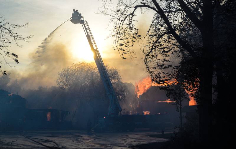 An aerial ladder truck sprays water Monday, May 30, 2022, onto the flames from the cabin fires at Grand Bear Resort in Utica.