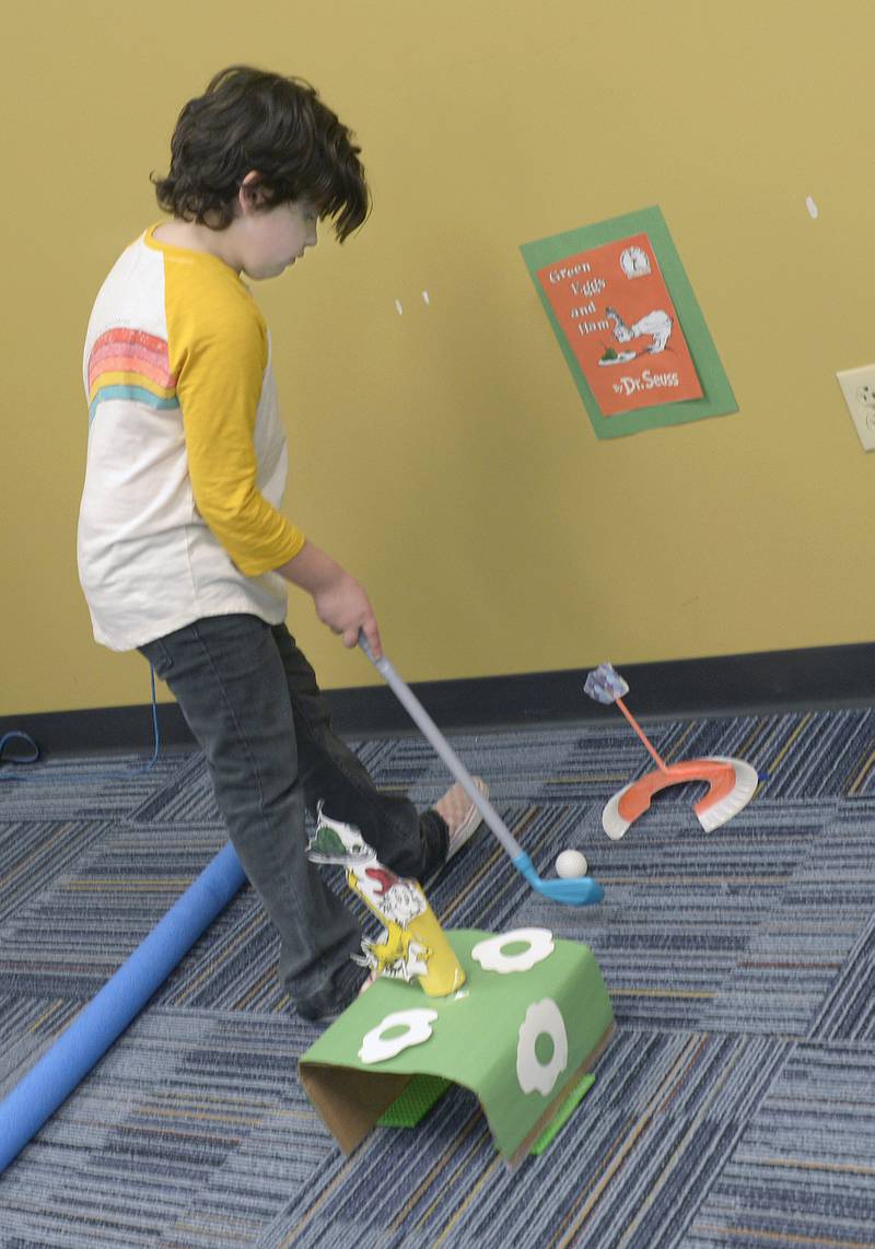 Everly Stebbins tries for par on the "Green Eggs And Ham" hole Thursday, March 7, 2024, at the Reddick Library in Ottawa during a special Dr. Seuss miniature golf outing to celebrate the author’s recent birthday.