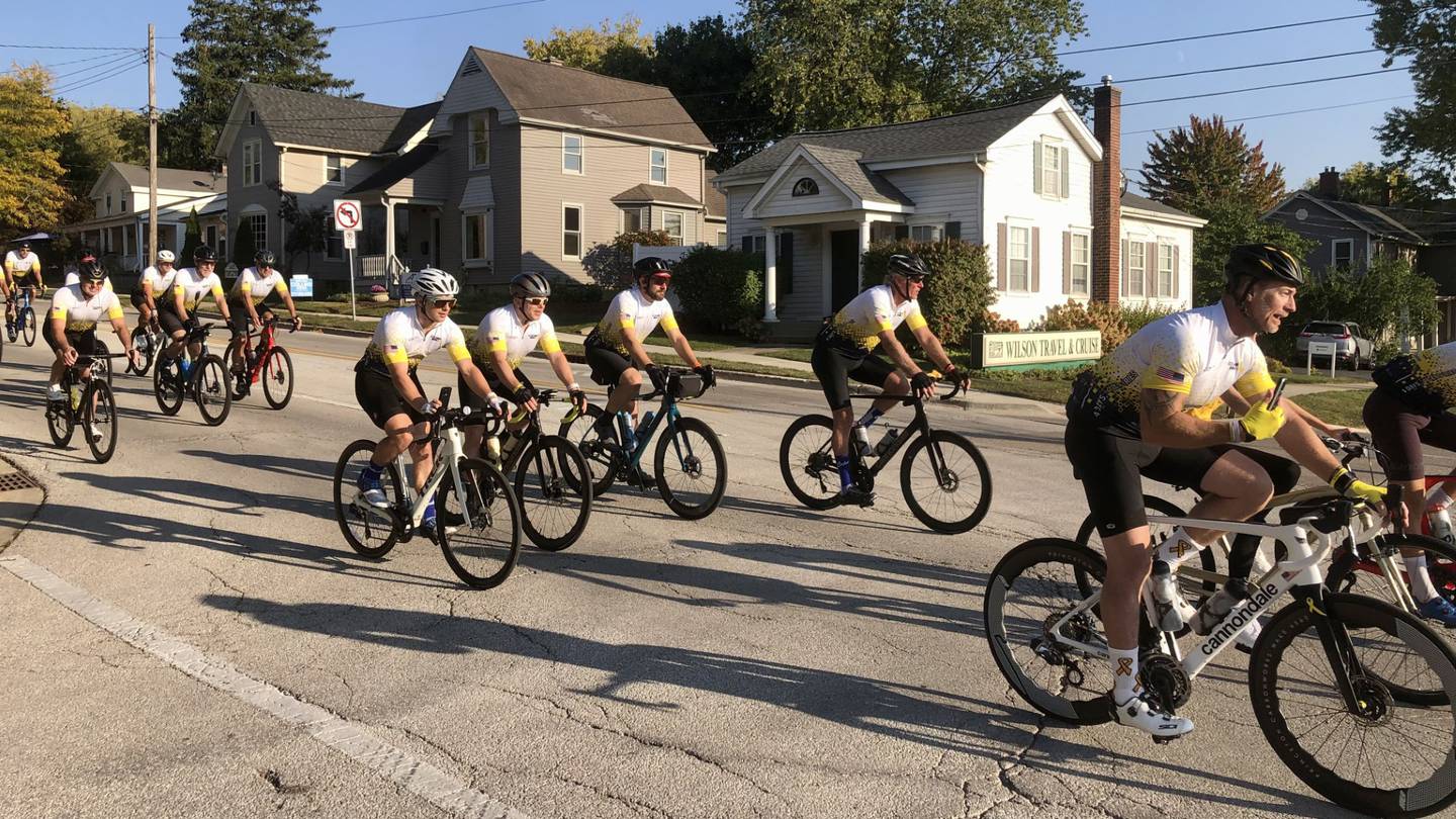 Cyclists pedal through the final stretch of a 475-mile charity bike ride for pediatric cancer at the corner of Illinois Street and Riverside Avenue in St. Charles on Oct. 10, 2024.