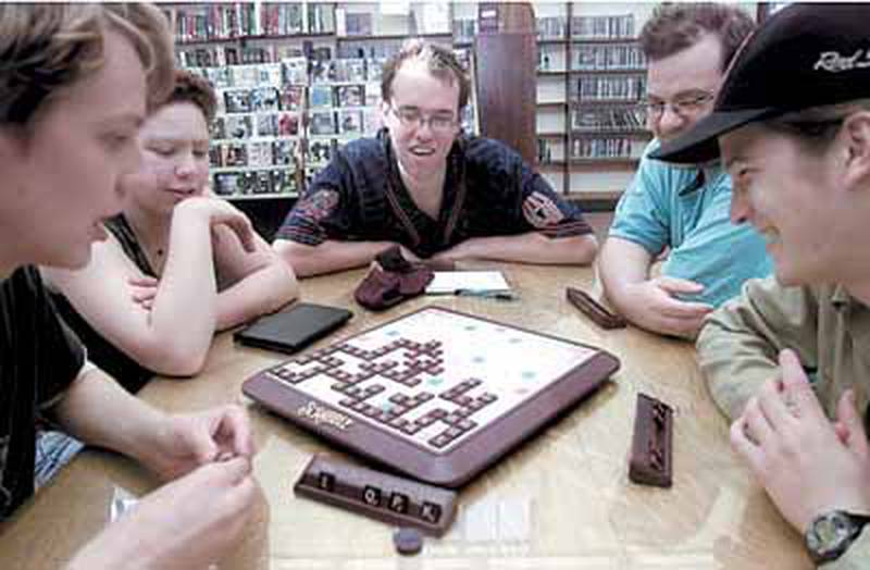 A group of board-game enthusiasts enjoy playing “Scrabble” Wednesday night during the DeKalb Public Library’s Family Game Night. DeKalb resident and attendee Sarah Ott, 23, said she prefers traditional board games to new games. “The older ones are simpler so there’s more room for variation,” Ott said. “The more complicated the rules, the more static the game is.” Chronicle photo KATE WEBER