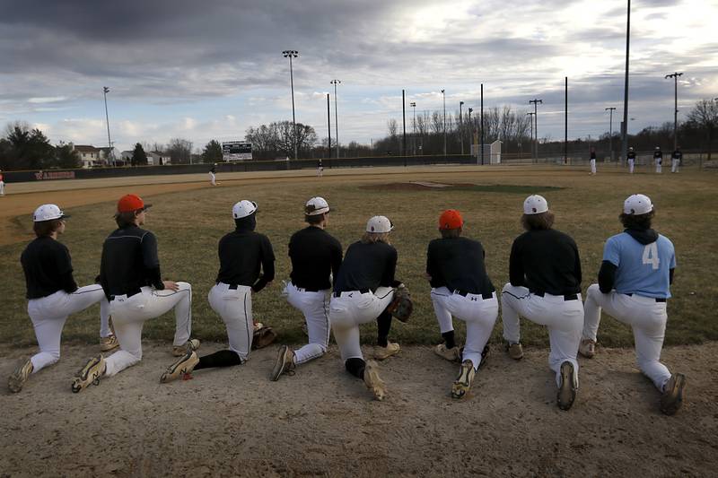 McHenry baseball players take a knee as they watch their teammates practice Wednesday, March 8, 2023, at Petersen Park in McHenry.