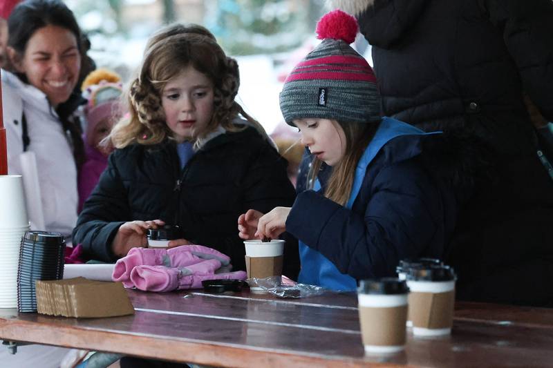 Beatrix Cody, left, and Calleigh McCrindle enjoy hot chocolate at Plainfield’s holiday kickoff Grinchmas on the Green on Saturday, Dec. 5, 2025 in Plainfield.