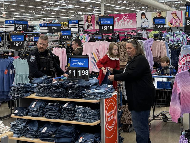 Channahon Police Chief Adam Bogart and a volunteer from Grundy County Heroes and Helpers helps Evelyn and Zeke look for pants for the Shop with a Local Hero event.
