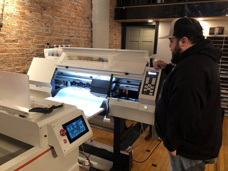 The direct to film printing machine makes a new custom design as co-owner Joshua Callaway supervises it on Thursday, March 9, 2023 at PersonaliTees in downtown Ottawa.