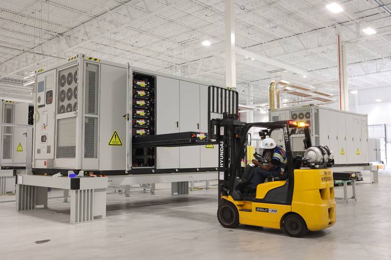 A worker precisely places a pack of battery modules into a large energy-storage system at Gotion Illinois in Manteno on Oct. 1, 2025.