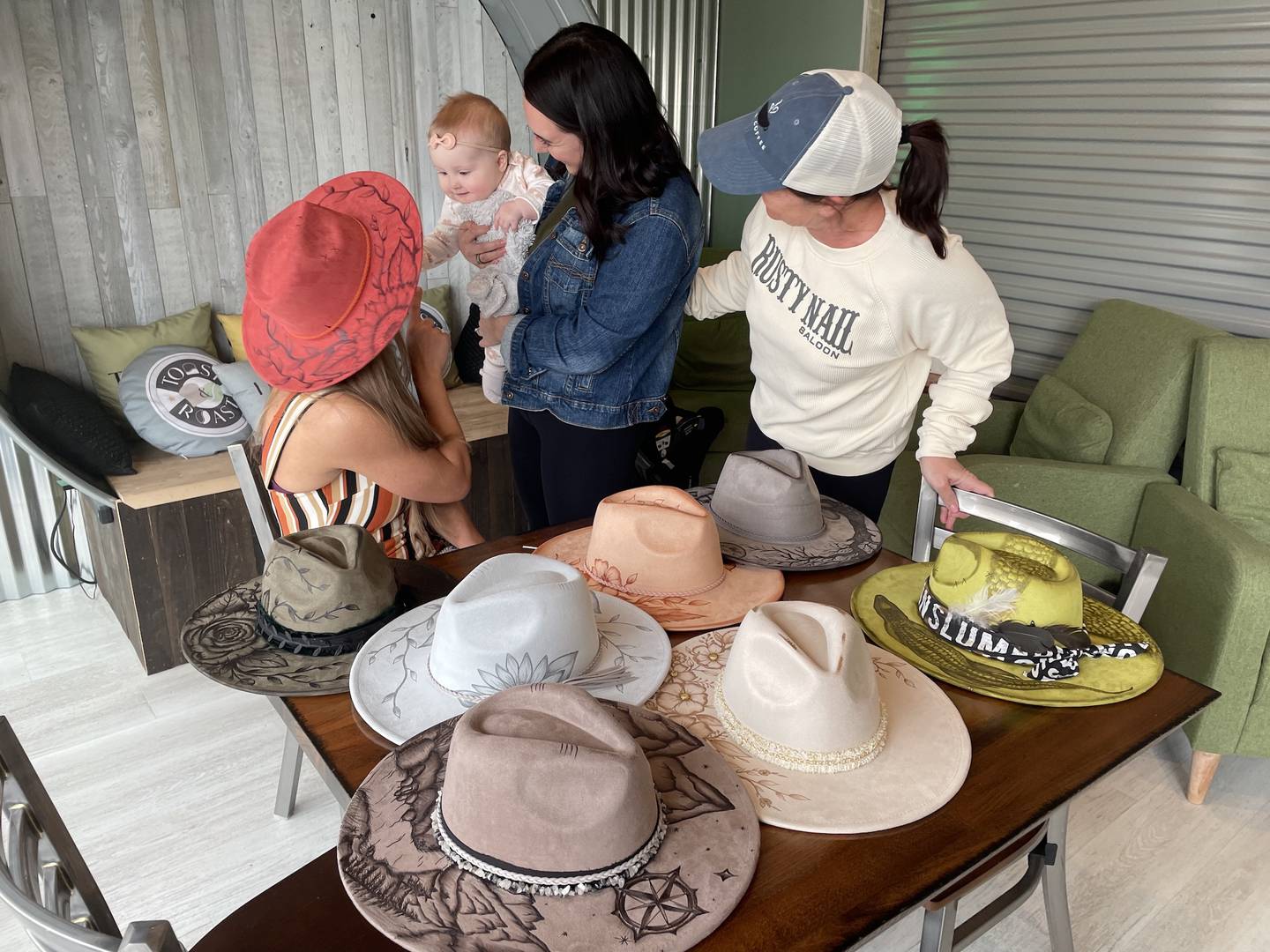 Karolyn Stahl, her daughter, Kara Hoffmann, and Hoffman's daughter, Blakely, all of Johnsburg, were among Toast & Roast coffee shop customers drawn to Lauren Sharp's hats as Sharp sat down for an interview to talk about her business, Art for Adrienne, and her mental health awareness advocacy.