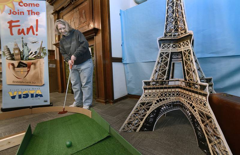 Sheryl Liss works to sink a putt Saturday, Jan. 21, 2023, near the Eiffel Tower  during the Streator Public Library’s inaugural mini-golf fundraising event. Each hole was sponsored by a local business.