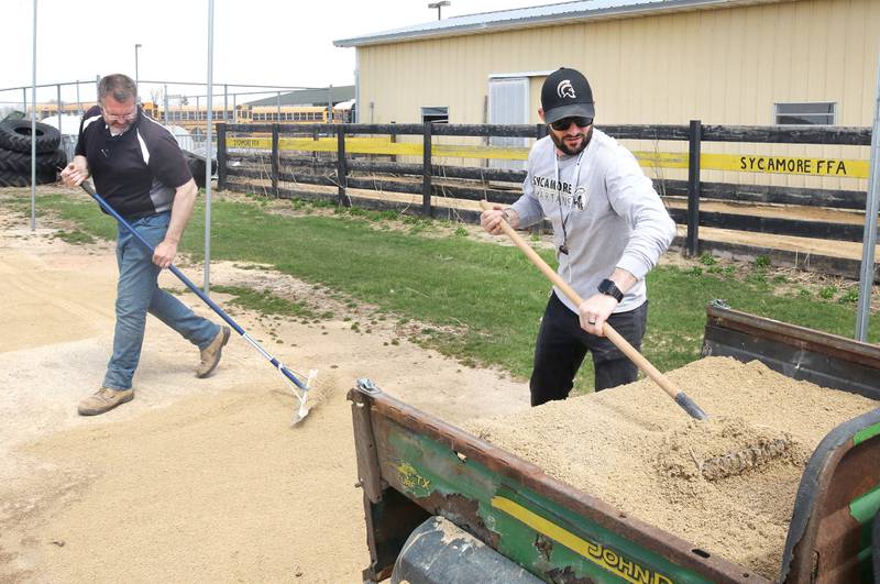 Mark Ekstrom, (left) director of buildings and grounds for Sycamore Community School District 427, and Scott Winter, warehouse manager, rake dirt into low spots Tuesday, April 11, 2023, in the batting cage behind the softball field at Sycamore High School.
