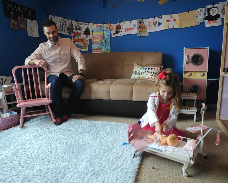 Everly Backe, 4, who has had multiple open heart surgeries to correct congenital heart defects, plays with a doll Friday, Feb. 11, 2022, as her father, Matt Backe, watches in their Crystal Lake home. As Everly has became more aware of her chest scar, which they call her "zipper," her dad, Matt, recently decided to get a tattoo that matches his daughter’s scar from her surgeries so she does not feel alone in having the scar.