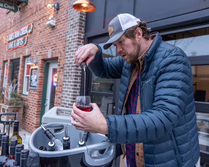 Travis Pour precisely pours wine into glass at the wine walk on Feb. 14, 2026 on Mill Street in Utica.