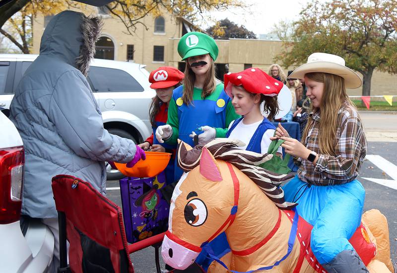 (l-r) Zoe Pfiffner, Jenna Johnston, Maddie Grueneberg and Teagan Murphu get candy at the 9th Annual Trunk or Treat at the Elburn Community Congregational Church on Sunday, Oct. 29, 2023 in Elburn.