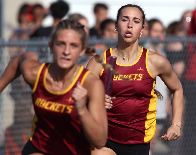 Richmond-Burton’s Kristina DeLeon, right, approaches teammate Sophia Komar  in the 400-meter relay during the McHenry County Track and Field Meet at McCracken Field on Thursday, April 24, 2025, in McHenry