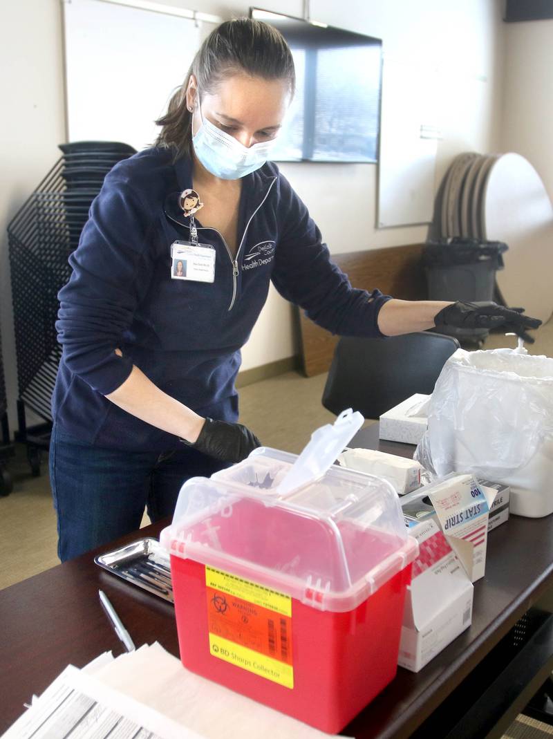 DeKalb County Health Department public health nurse Alex Diehl sanitizes her work station after administering an injection of the Moderna COVID-19 vaccine to a DeKalb firefighter Thursday in DeKalb.