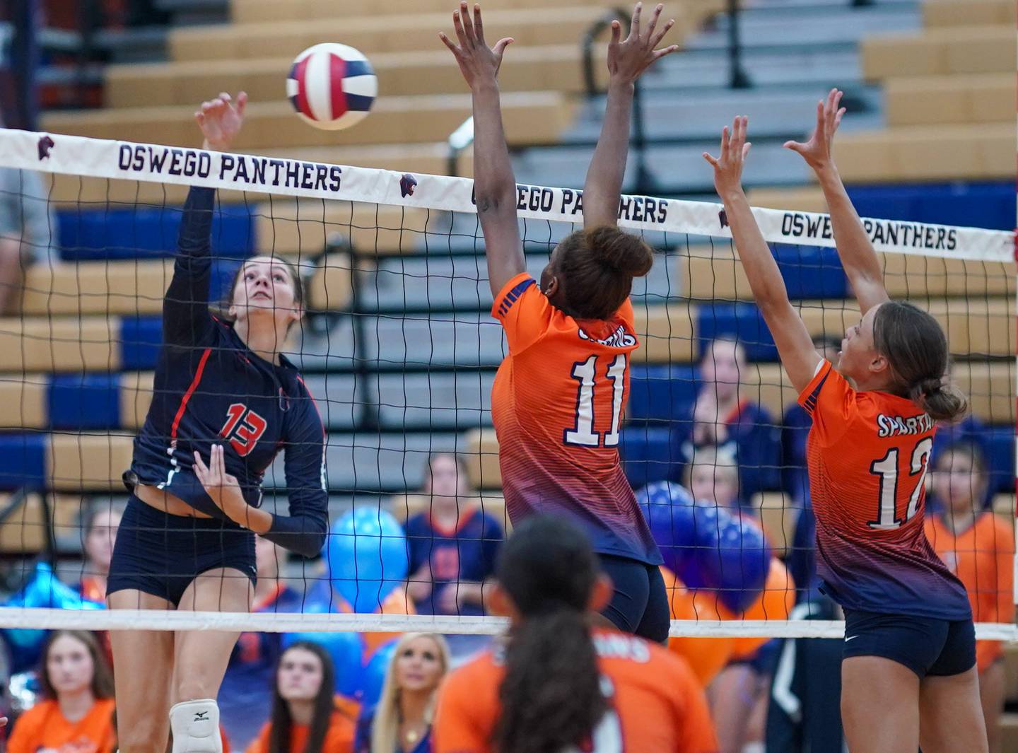 Oswego’s Sidney Hamaker (13) goes up for a kill against Romeoville's Grace Griffin (11) and Taylor Cicero (12) during a volleyball game at Oswego High School on Tuesday, Oct. 17, 2023.