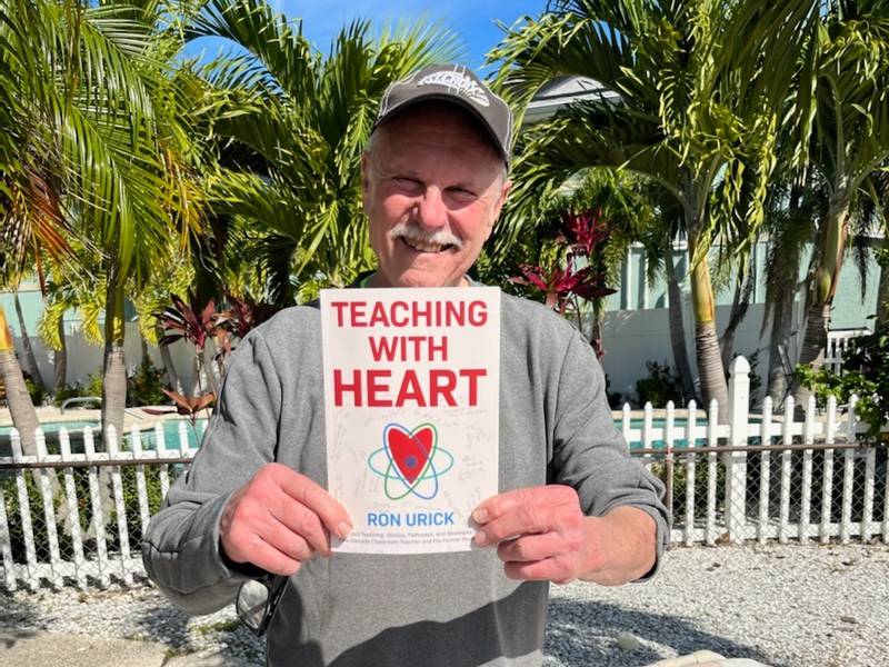 Prairie Grove resident Ron Urick poses while on vacation in Florida with a copy of his new self-published book, "Teaching with Heart," on Thursday, Jan. 6, 2022.