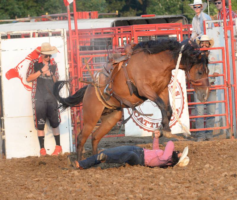 A cowgirl falls to the ground after being bucked off a horse in the bronc riding event at the  T & A Bucking Bulls Rodeo during the Ogle County Fair on Friday, Aug. 1, 2025 in Oregon.
