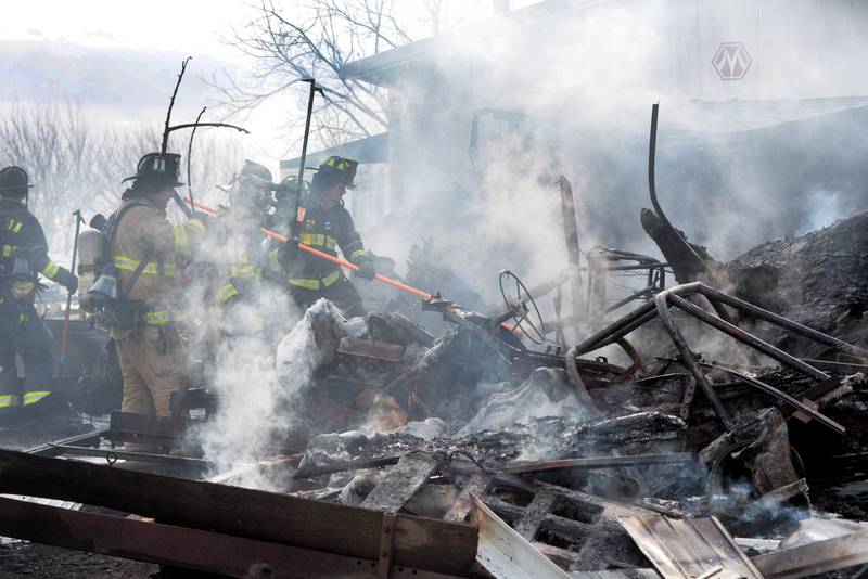 Firefighters look for hot spots during a garage fire at 6727 W. Henry Road, southeast of Polo, on Wednesday, March 26, 2025. Several departments responded to the fire at the rural residence. A camper,  Jeep, and other items located inside and around the garage were destroyed. No injuries were reported.