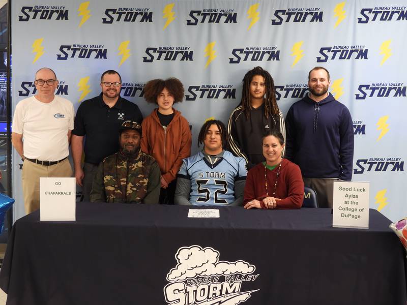 Bureau Valley senior Ayize Martin signs to play football for the College of DuPage on Tuesday. He was joined by his parents, Virgil Martin and Chantel Brennan, his sister, Rashida, and brother, Dakari, and Storm coaches Craig Johnson (back row, from left), Mat Pistole and Philip Przybyla.