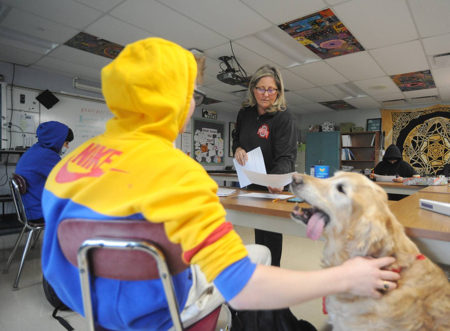 Teacher Anne Whitney-Turbidy answers student Eli Fecarotta’s question as he pets Henry, the class therapy dog, as she teaches about food labels during a health class Tuesday, April 19, 2022, at Haber Oaks Campus in Crystal Lake.