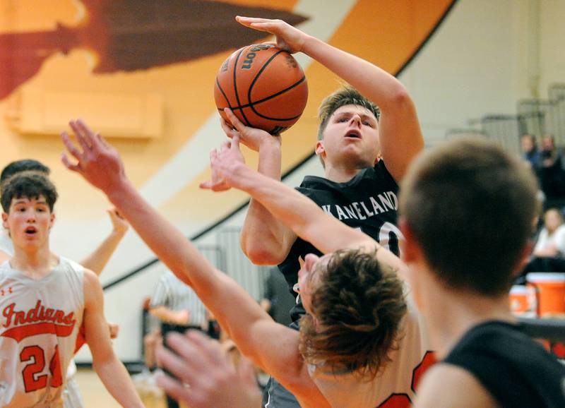 Kaneland's Troyer Carlson (10) drives for a shot and knocks over Sandwich defender austin Marks during a boys' basketball game at Sandwich High School on Friday, Jan. 13, 2023.