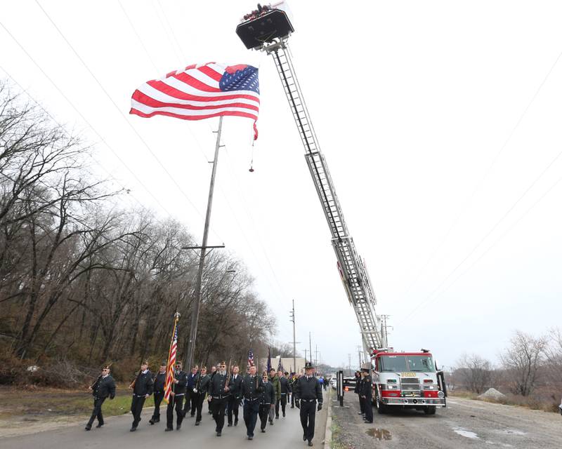 Veterans march underneath a large American Flag provided by the Peru Fire Department down Water Street in the 44th annual Pearl Harbor parade and memorial ceremony on Saturday, Dec. 2, 2023 in Peru.