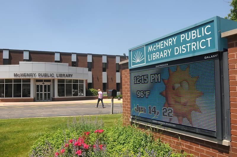 A woman walks into McHenry Public Library on Tuesday, June 14, 2022, while the current temperature is shown on the sign.