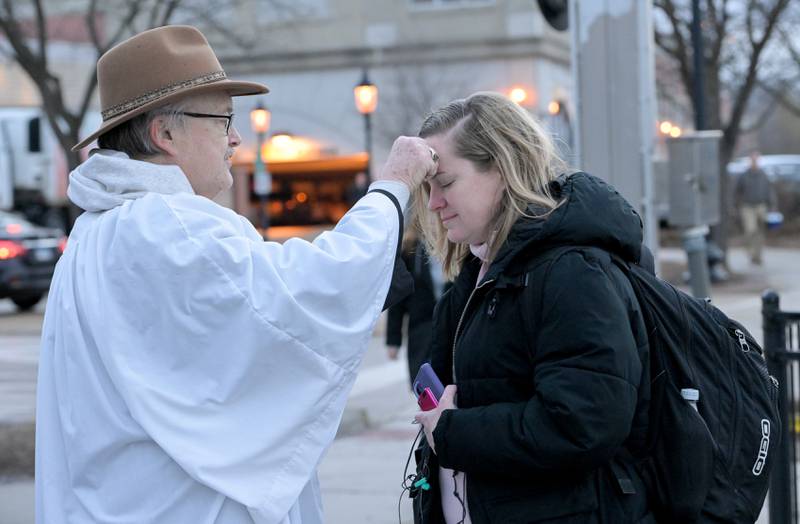 Lee Kolodziej from St. Charles Episcopal Church administers ashes to Elizabeth Larson of Batavia at the Geneva train station on Wednesday, Feb 18, 2026.