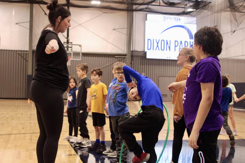 Brooke Francque leads a session of the Dixon Park District's Winter Mini Spark day camp at the Facility on Tuesday as she instructs children on how to pass their body through a Hula Hoop without breaking a human chain.