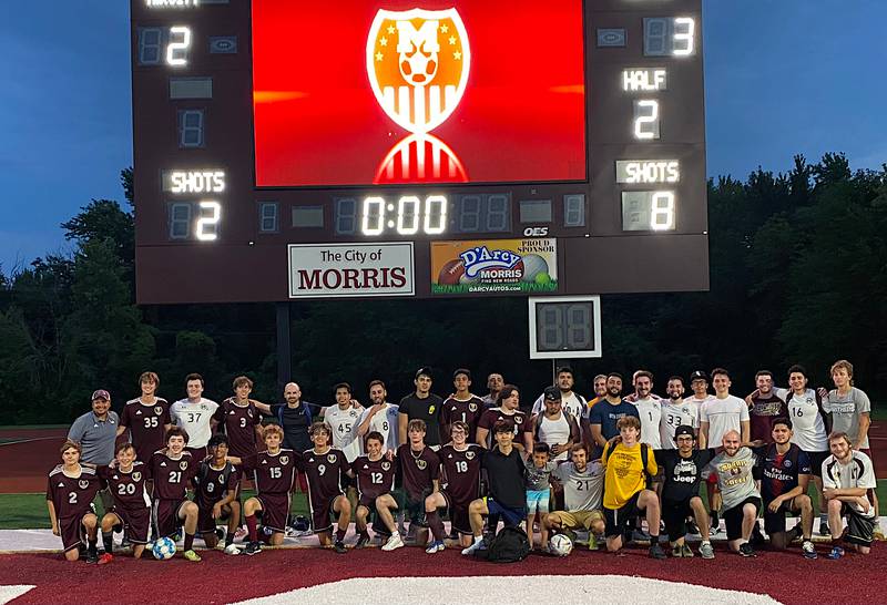 Members of the Morris varsity boys soccer team pose with alumni after playing an alumni game Saturday at Morris Community High School.