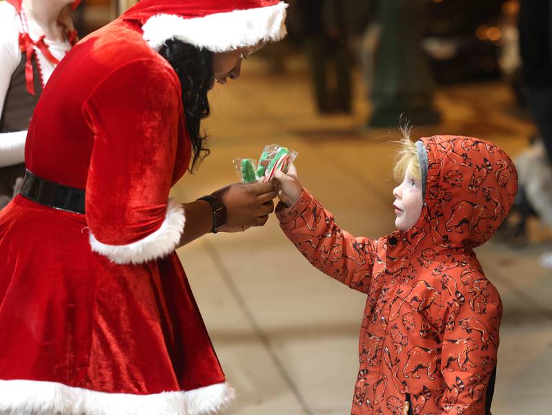 Jameson Rexford, 5, from Sycamore, gets some candy from Aaliayah Bomar, from Ovation Performing Arts Studio, Friday, Nov. 21, 2025, during Moonlight Magic in downtown Sycamore.