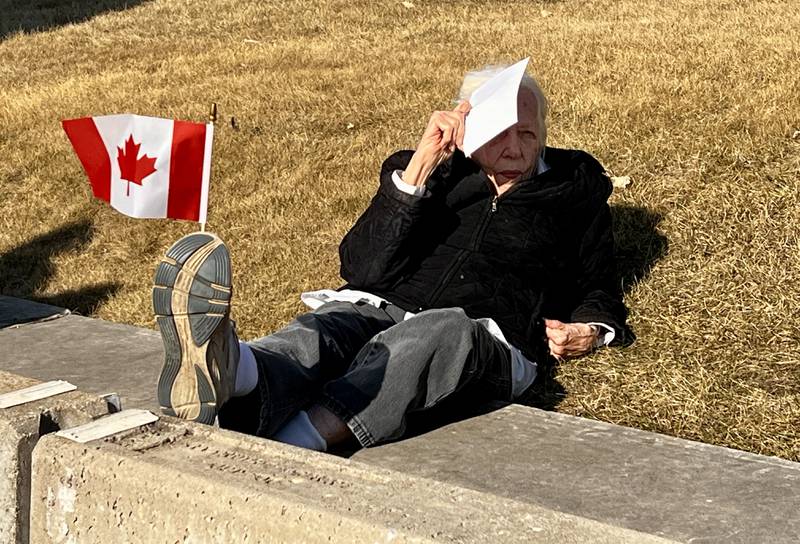 Frances Ayars sits on the lawn of the Old Lee County Courthouse in Dixon during a vigil for Ukraine on March 13, 2025.