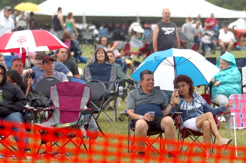 People brave raindrops as they watch the Heart to Heartbreaker band during the Rockin’ Rib Fest Friday at Sunset Park in Lake in the Hills.
