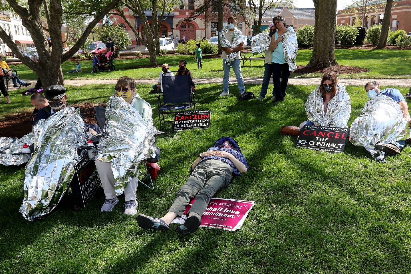 Attendees listen to speakers as some wrap themselves in a thin mylar sheet as symbolism and in solidarity with ICE detainees who are issued the same thin blankets while in custody. Approximately 80 people were in attendance at the rally to end McHenry County's contract with U.S. Immigration and Customs Enforcement on Saturday, May 1, 2021 in Woodstock.