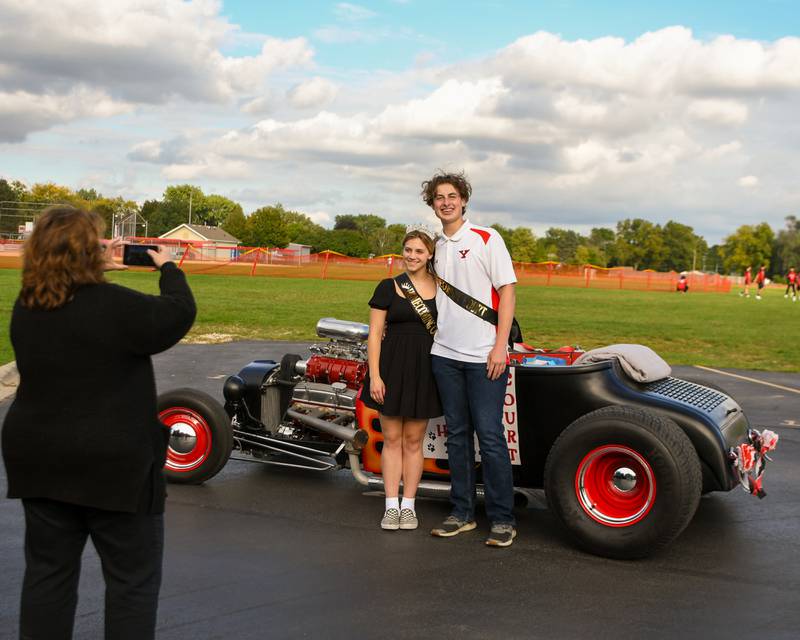 Homecoming court members and seniors at Yorkville High School Ryan Evans, right, and Delaney Phillips pose in front of a 1927 ford before the start of the Homecoming parade on Thursday, Sept. 28, 2023.