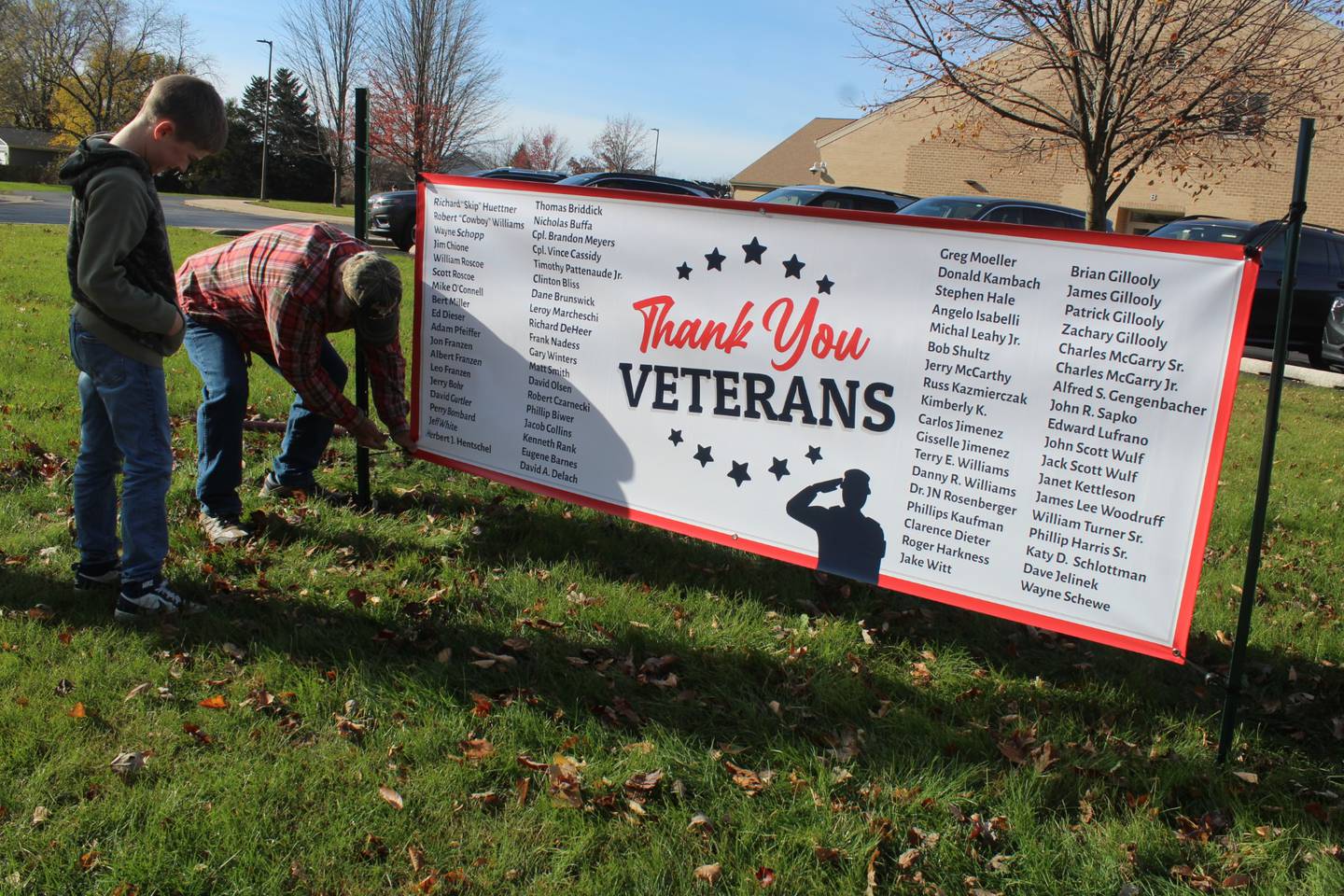 River View Elementary School fifth grader Henry Franzen watches his grandfather  Mike Murphy install a sign honoring veterans at the school on Friday, November 8, 2024. Henry raised more than $2,000 to put 192 flags and the sign in front of the school for Veterans Day.