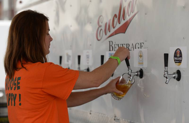Liz Stroud of Downers Grove pours beers for people attending the Downers Grove Octoberfest Saturday, Sept. 16, 2023.