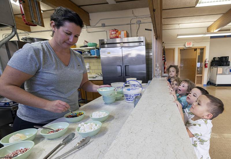 Carla Fiessinger, administrative assistant at St. Anne’s school, dishes up ice cream and sweet toppings to excited kids Tuesday, Jan. 28, 2025. The students were treated to the surprise in celebration of Catholic Schools Week.