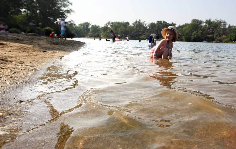 Emma Yurchyliuk, 3, of Lake in the Hills dons a beach hat as she ventures into the water during the First Day of Summer Beach Party at Indian Trail Beach Wednesday evening in Lake in the Hills.