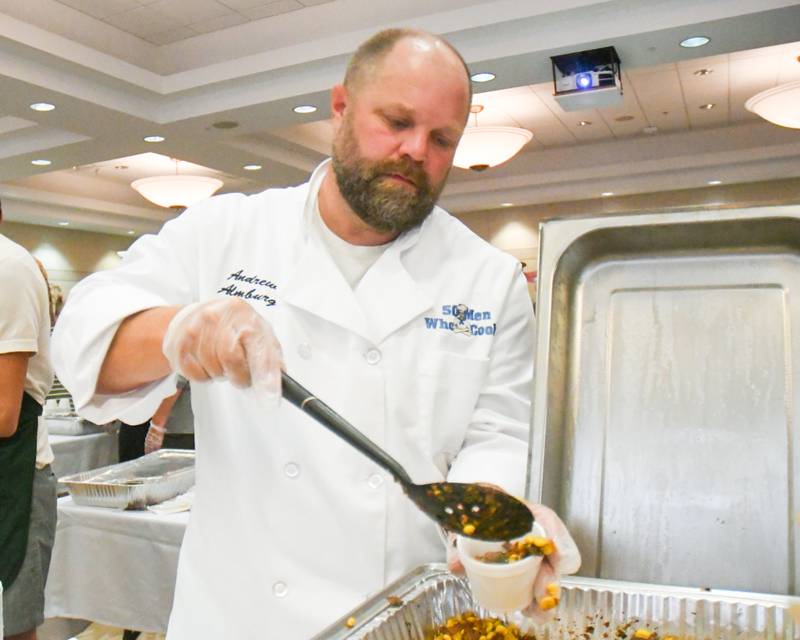 Chef Andrew Almburg, who was voted best entrée in 2019, dishes out his side dish of Texas corn during the 20th anniversary of 50 Men Who Cook, an annual fundraiser hosted by CASA DeKalb County at the Barsema Alumni and Visitors Center at Northern Illinois University in DeKalb on Saturday, Aug. 10, 2024.