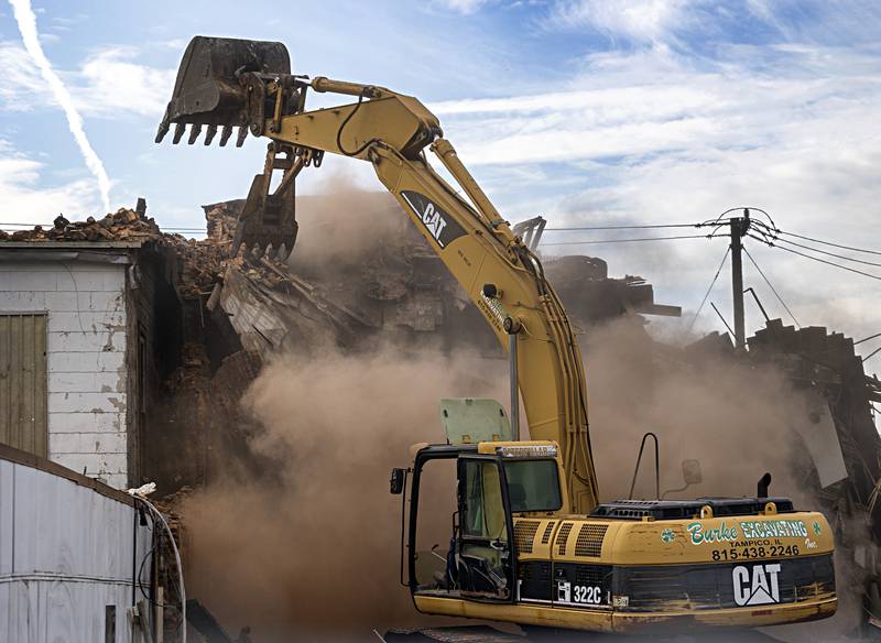 A plume of dust billows up after a large section of brick wall was torn down Tuesday, Sept. 5, 2023 during demolition of a fire ravaged building in Sterling.