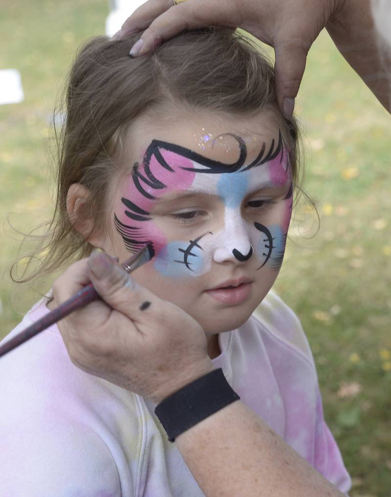 Althea Smith gets her face decorated Saturday, Sept. 28, 2024, by Wild Style Designs at Washington Square during the annual Scarecrow Fest in Ottawa.