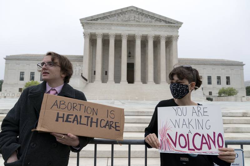 Demonstrators Jonah Smith from Calif., left, and Robin G. from the D.C. area, stand outside the U.S. Supreme Court early Tuesday, May 3, 2022 in Washington. A draft opinion suggests the U.S. Supreme Court could be poised to overturn the landmark 1973 Roe v. Wade case that legalized abortion nationwide, according to a Politico report released Monday. Whatever the outcome, the Politico report represents an extremely rare breach of the court's secretive deliberation process, and on a case of surpassing importance. (AP Photo/Jose Luis Magana)