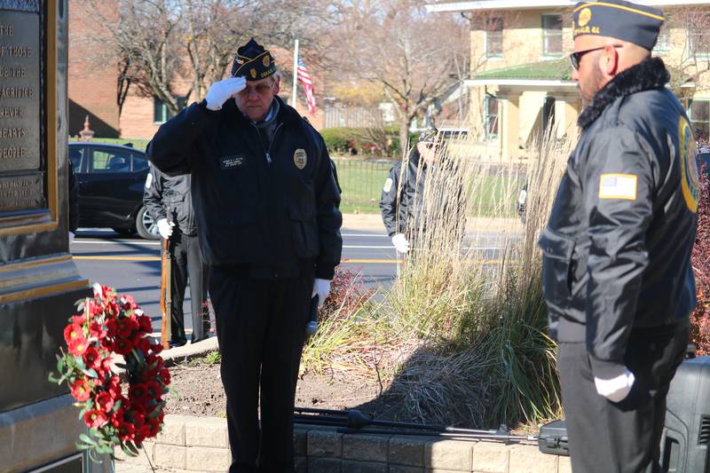 Veterans Manuel Olalde (right) looks at a wreath posted on a stand as Mike Embrey (left) stands in salute during a Veterans Day ceremony held in downtown DeKalb Nov. 11, 2022.