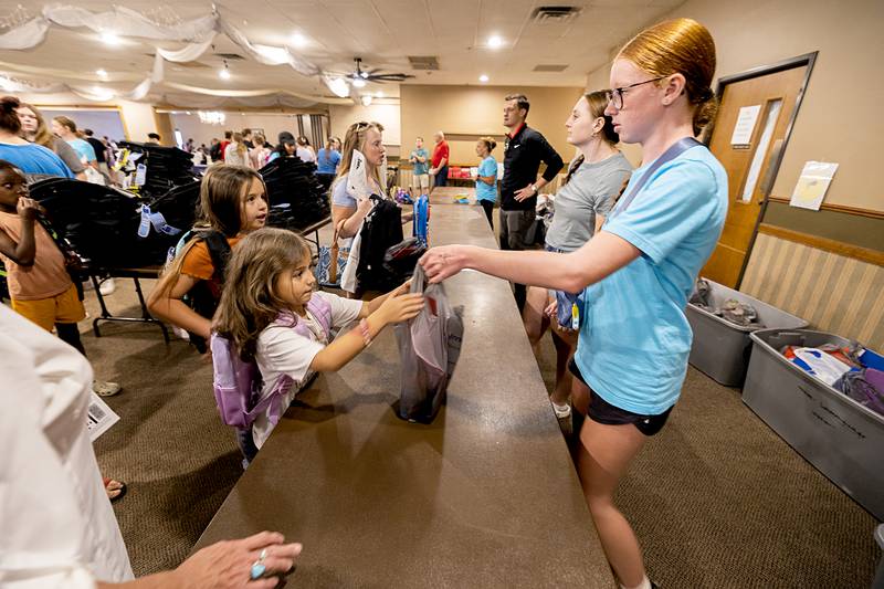 Cayley Dallas, 13, hands Aria Chacon, 6, a bag of school supplies Thursday, Aug. 8, 2024 during the Tools for Schools distribution.