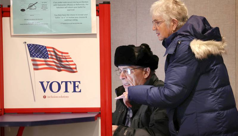 Richard Dowen, from DeKalb, gets some help using the touchscreen voting machine from his wife Peggy as he casts his ballot in the primary election Tuesday, March 17, 2026, at the DeKalb County Administration Building in Sycamore.